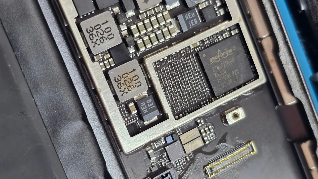The iPhone 13 Pro Max logic board from this recovery on the Phone Studio bench in Courtice, with a chip lifted off and the bare BGA solder pad array exposed