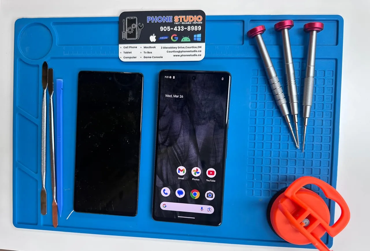 Google Pixel phone on the Phone Studio repair bench in Courtice, beside the shop's business card and repair tools