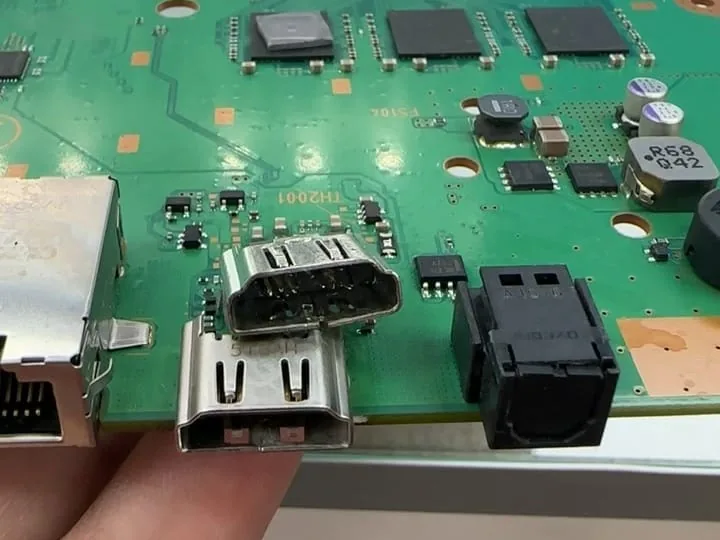 Two HDMI ports at the edge of a PS4 board, one resting on the board and one held up to it, at Phone Studio in Courtice